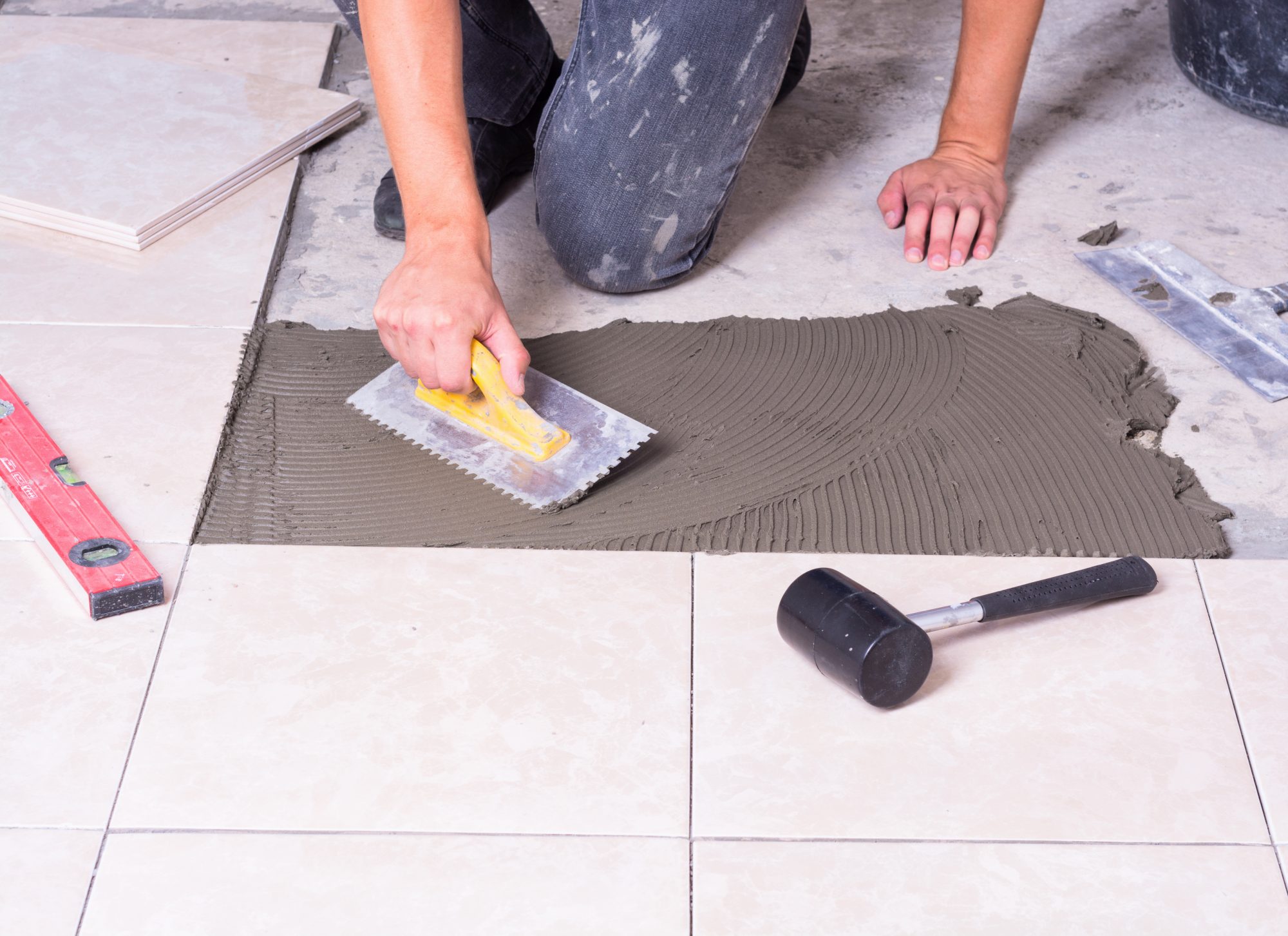 Tiler using tools to install ceramic tiles on a floor