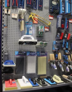 A wall with multiple tools and tiling accessories displayed on it.