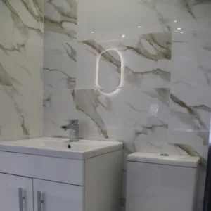 White marble wall tiles in a bathroom that includes a sink and toilet.